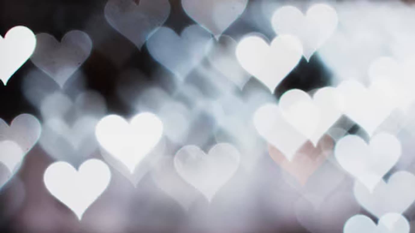Soft white heart-shaped bokeh lights on a dark background
